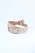 A cream/light pink leather purse strap with a gold buckle wrapped in a coil