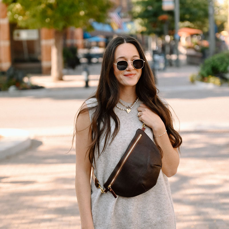 Model wearing a zippered, dark brown leather cross body bag 