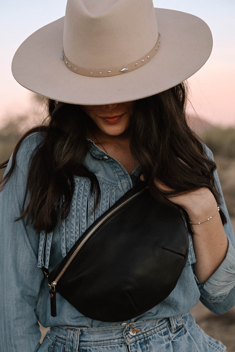 Model wearing a zippered black leather cross body bag.