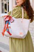 Model in green dress displaying birch white leather tote bag with cream colored handles and accent scarf