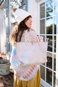 Model wearing a cozy clothing with a large birch white leather tote thrown over her shoulder. Tote has cream colored straps