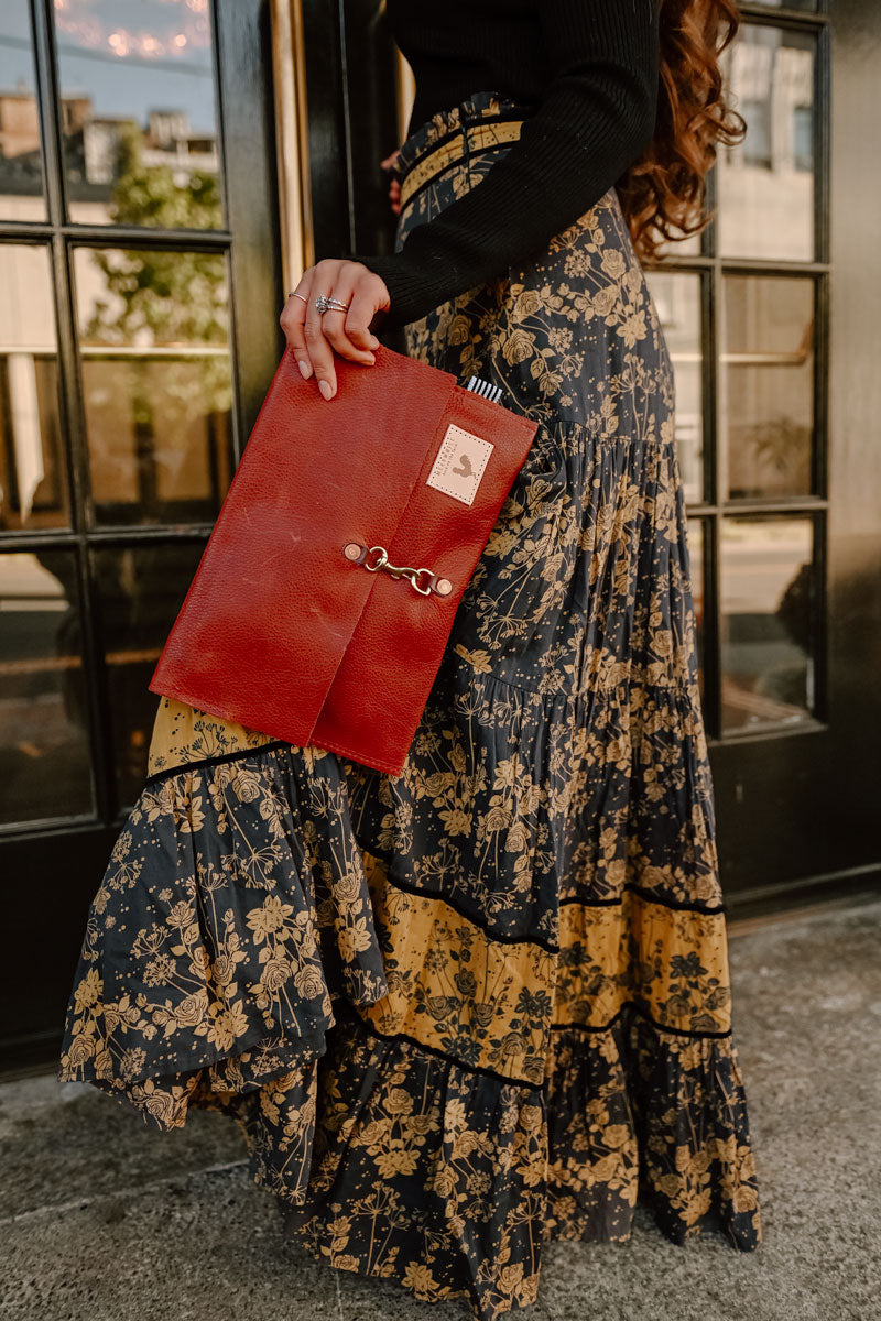 Model holding medium sized fold over style red leather clutch with antiqued clasp