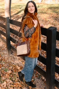 Model displaying dark brown leather handbag with cream colored brushed leather front pocket.