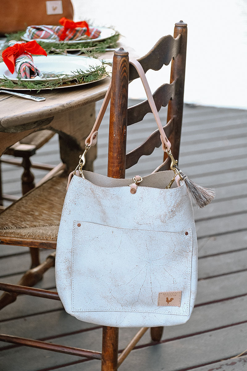 Model wearing white shoulder bag with extra cream colored strap.