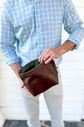 Man holding a small brown leather hand bag