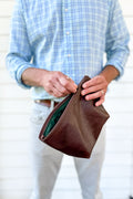 Man holding a small brown leather hand bag