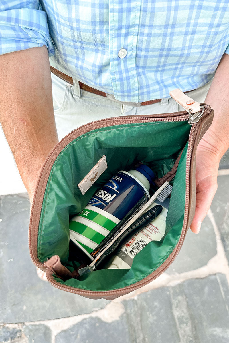 Green lining of a small brown leather hand bag with miscellaneous items (golf balls, glove, pick)