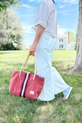 Girl holding an orange leather large tote bag with a red/white stripe in the middle