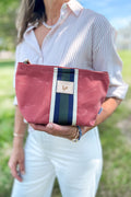Girl holding a small orange leather clutch/pouch bag with a green/white stripe in the middle