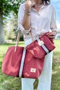 Girl holding an orange leather large tote bag with a red/white stripe in the middle and a matching small pouch/clutch