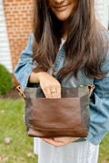 Woman reaching into the back pocket of a brown/camo leather purse