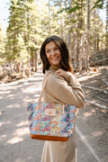 Model wearing floral quilted bag with cream colored handles and tan leather bottom