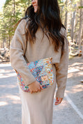 Model holding medium sized quilted floral handbag with no handles or straps