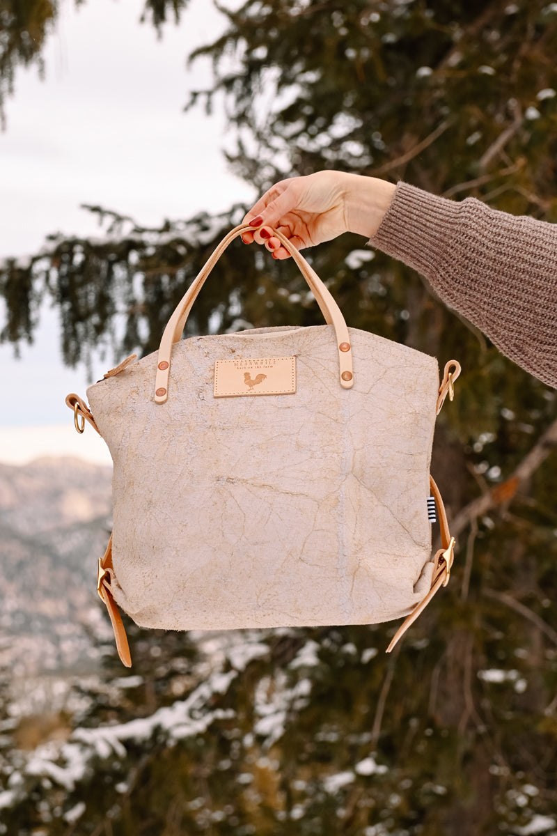 Woman wearing the birch white backpack with meanwhile logo and light brown straps.