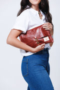 Model holding medium sized fold over style red leather clutch with antiqued clasp