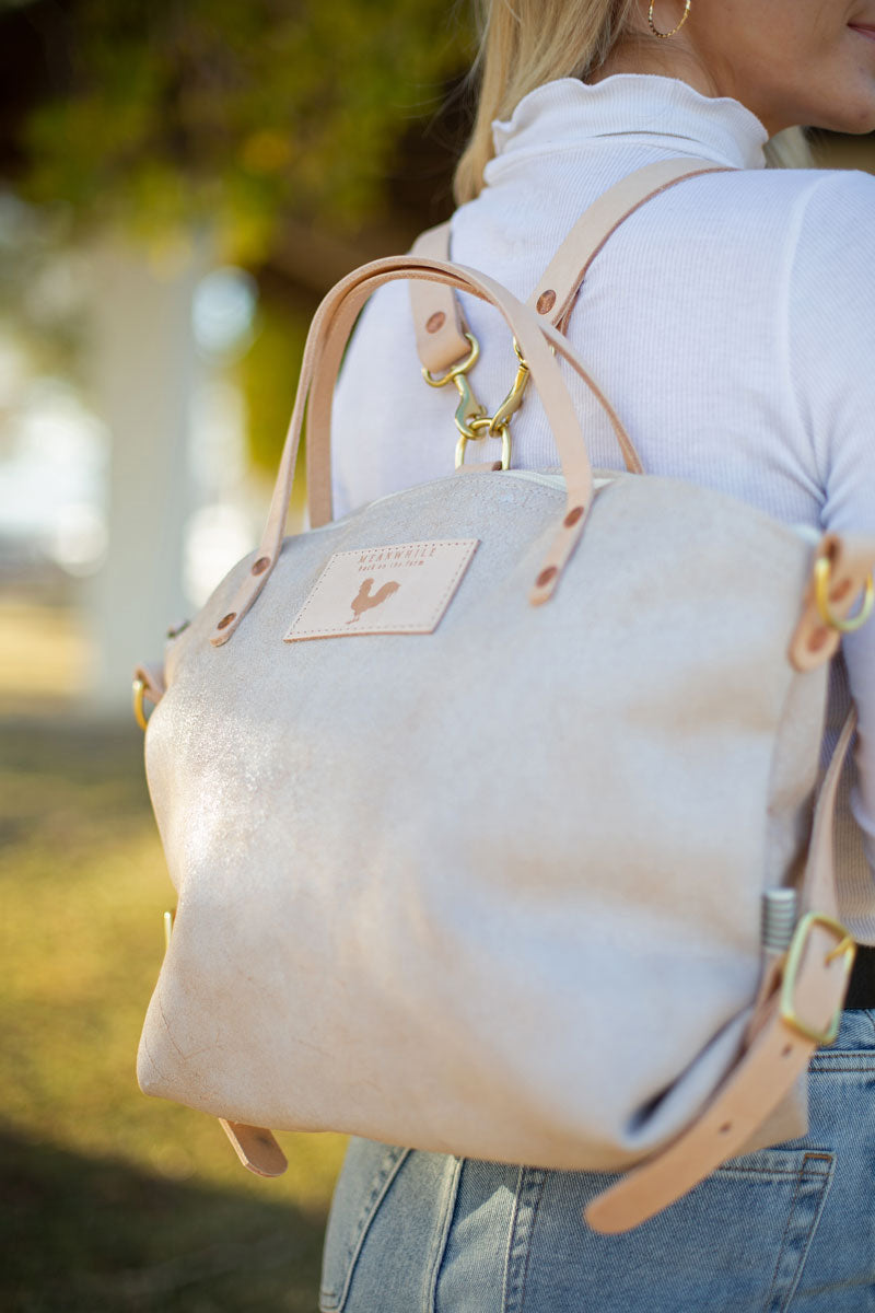 Woman wearing the birch white backpack with meanwhile logo and light brown straps.