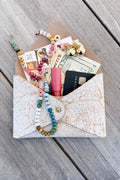 Picture of birch white leather keepsake clutch. Clutch is full of credit card, cash, lip gloss, jewelry and pictures.