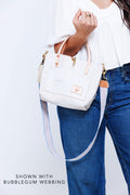 Woman holding a small white birch leather purse with a light blue/yellow/pink webbing crossbody strap attached to it