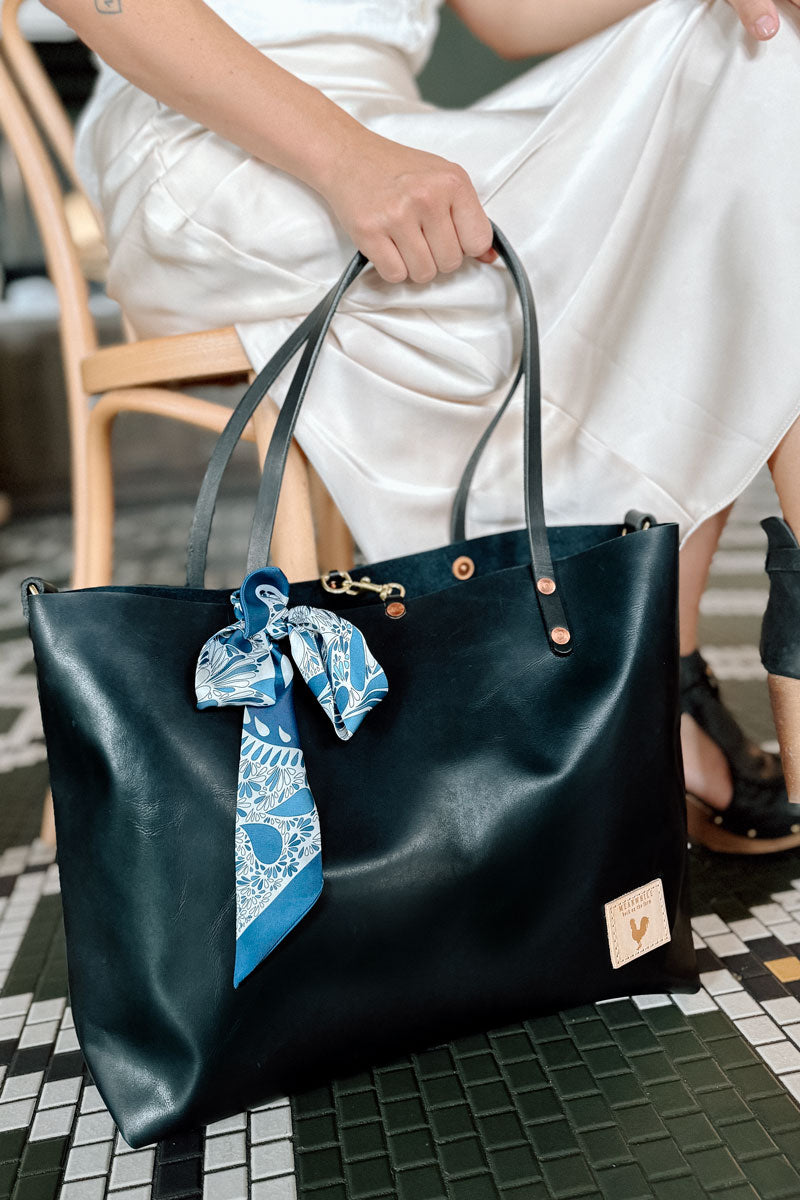 Woman holding black leather tote bag