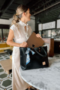 Woman holding black leather tote bag