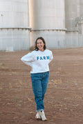 Model in front of silos wearing a white sweatshirt that reads 