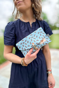 Girl holding a light blue envelope clutch/purse with small brown horses pattern