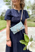 Girl wearing a light blue envelope clutch/purse across her chest with small brown horses pattern