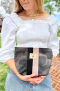 Girl holding a small black camo leather makeup bag with a black/cream stripe
