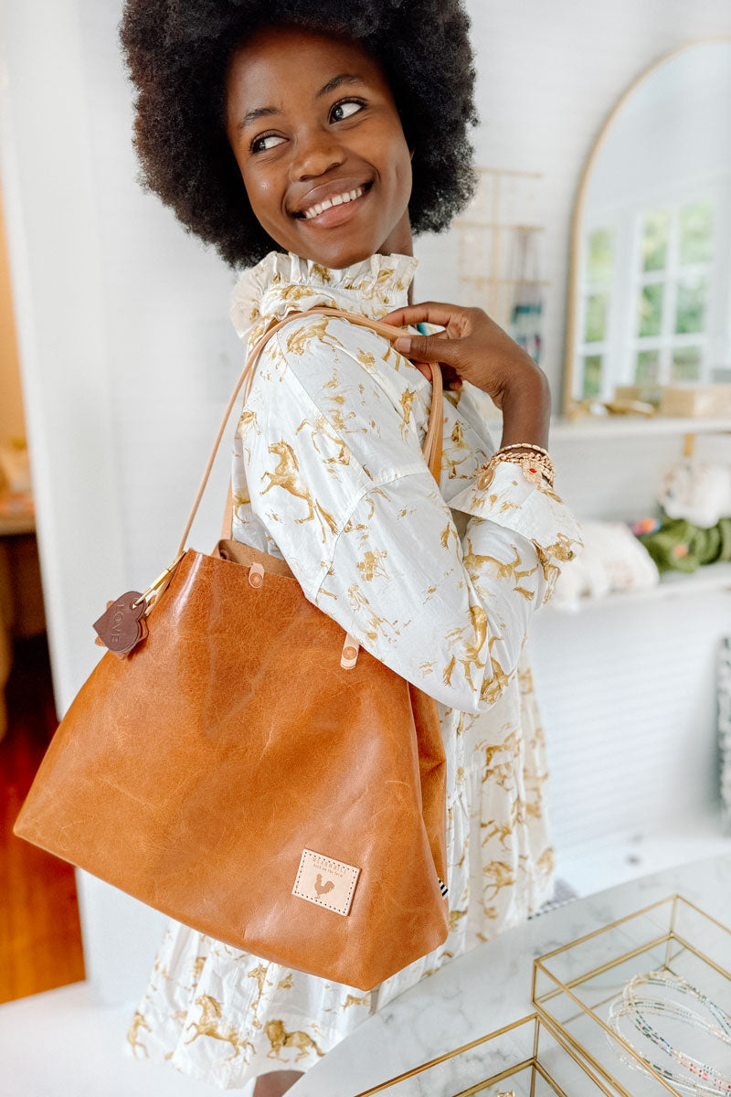 Woman smiling reaching into a big light brown leather tote bag