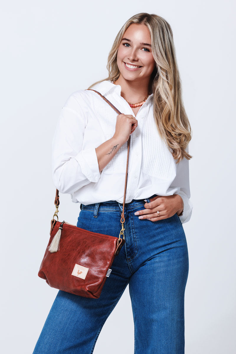 Model wearing ruby red leather bag with a long shoulder strap