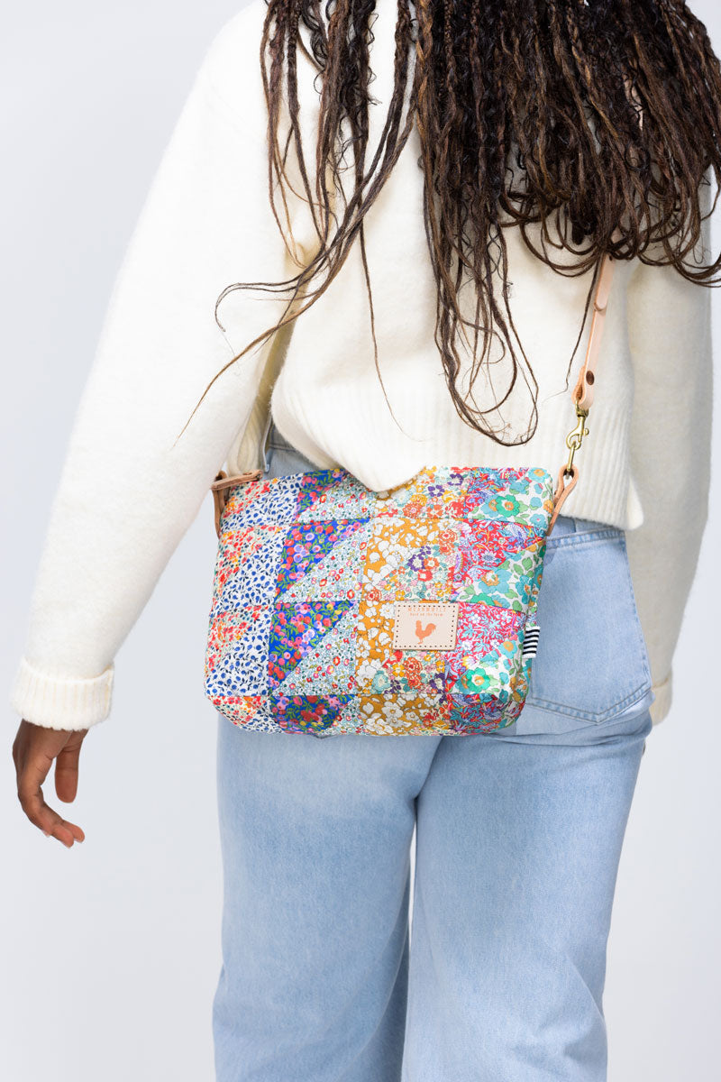 Rear view of model wearing a floral quilted medium sized handbag with hip length straps