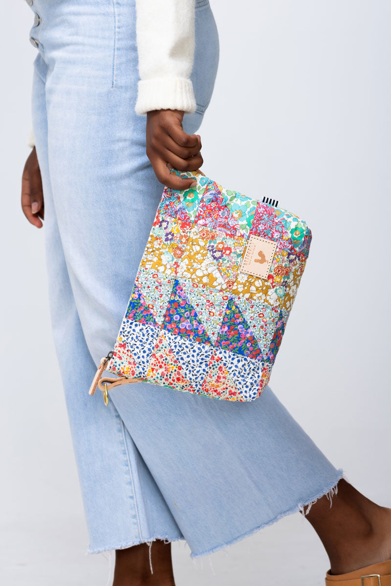 Model holding large quilted floral clutch by the corner