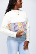 Model holding large floral quilted clutch in front of her torso