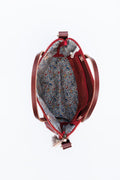 Picture of interior of ruby leather bag. Bag is lined with a busy floral print and a zippered side pocket