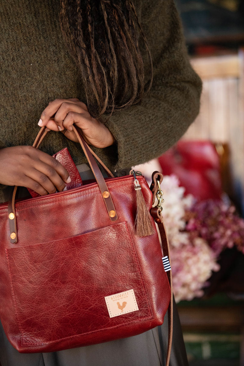 Woman putting a red leather envelope wallet into a red/brown leather small tote