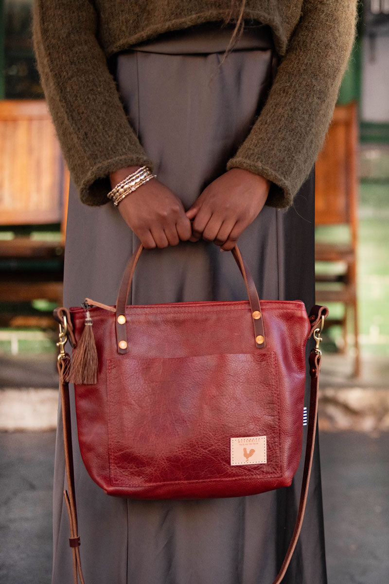 Woman holding a red/brown leather small tote